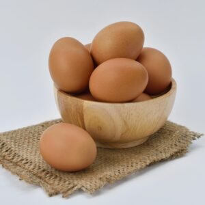 High resolution image of brown eggs in a wooden bowl placed on burlap fabric, ideal for food-themed content.